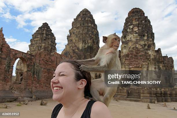 Monkey prepares to jump off tourist Katie Myers of the US at an ancient temple during the annual "monkey buffet" in Lopburi province, north of...