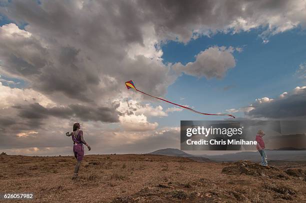 maasai warrior flying a kite with a boy - rift valley stock pictures, royalty-free photos & images