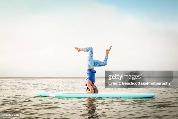 paddleboard headstand bent knees - practioners enjoy serenity of paddleboard yoga stockfoto's en -beelden