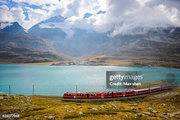 overlooking view of train running on the bernina railway in switzerland. - switzerland train stock pictures, royalty-free photos & images
