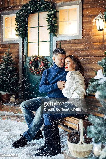 lovers embracing on a background of their house - woman snow outside night stockfoto's en -beelden