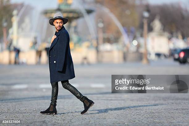 Theo Kimbaloula , is wearing a Sand Copenhagen mesh t-shirt, The Kooples black jeans, Keiro black shoes, a Daniel Wellington watch, a Saudade Paris...