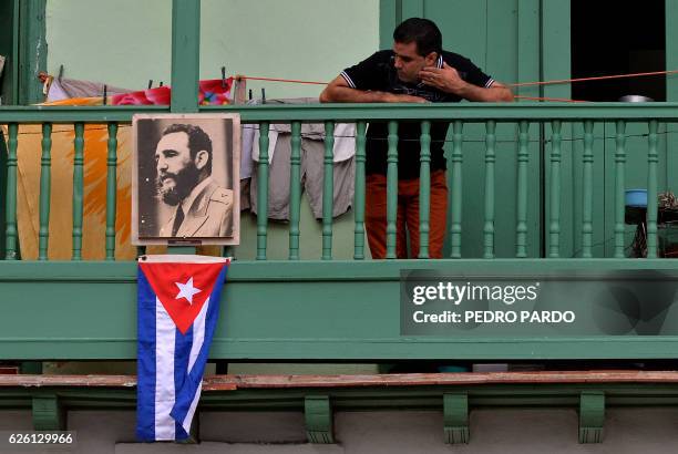 Man remains in a balcony next to a picture of Cuban revolutionary leader Fidel Castro at San Francisco de Asis Square in Havana, on November 27, 2016...