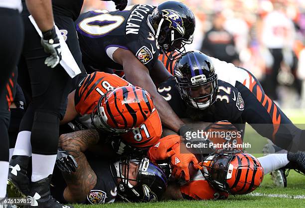 Running back Jeremy Hill of the Cincinnati Bengals is tackled by strong safety Eric Weddle outside linebacker Albert McClellan of the Baltimore...