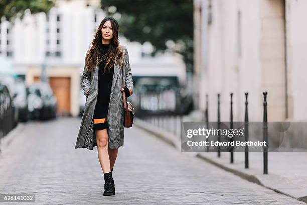 Sofya Benzakour , is wearing an Asos black dress with orange lines, an H&M gray long coat, River Island black boots, and a C&A brown bag, in the area...