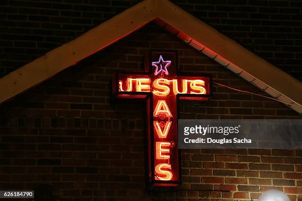 'jesus saves' illuminated neon sign - evangelikalismus stock-fotos und bilder