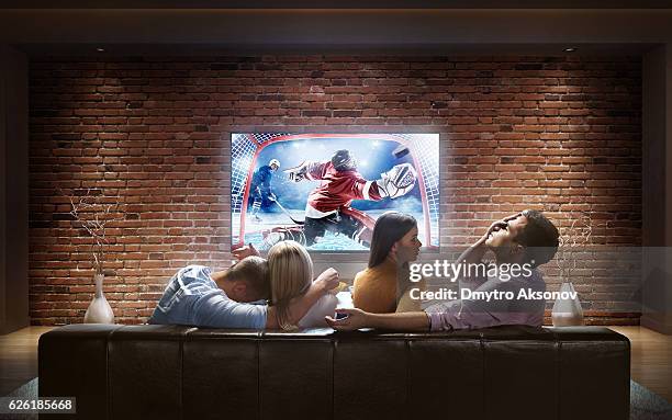 couples watching ice hockey game at home - hockey season celebration stock pictures, royalty-free photos & images