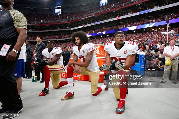 Eli Harold, Colin Kaepernick and Eric Reid of the San Francisco 49ers kneel on the sideline, during the anthem, prior to the game against the Arizona...