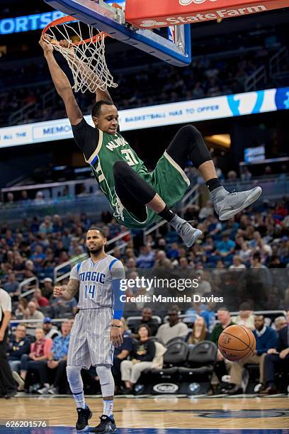 John Henson of the Milwaukee Bucks hangs on the basket after his dunk in the second half of the game against the Orlando Magic at Amway Center on...