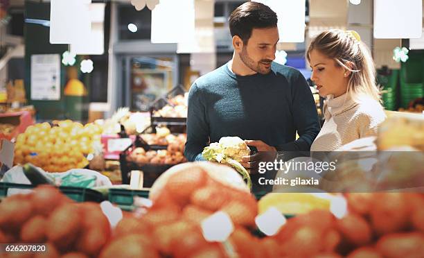 couple in supermarket buying vegetables. - market retail space stock pictures, royalty-free photos & images