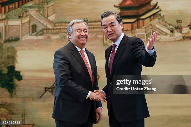 Chinese Foreign Minister Wang Yi shakes hands with United Nations Secretary General-designate Antonio Guterres after a joint press conference at the...