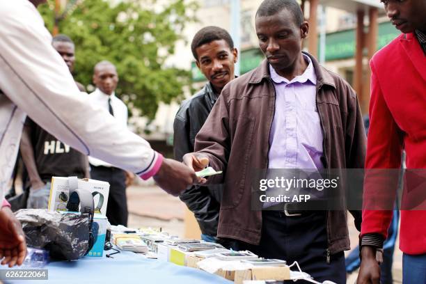 Man pays a purchase with a two-dollar note that he withdrew at Cabs Bank in Harare central business centre on November 28, 2016. - Zimbabwe issues...