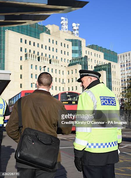 Police officer speaks to a commuter in front of the Secret Intelligence Service building, the headquarters of MI6, at Vauxhall Bus station in south...