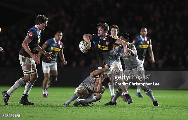 Jack Clifford of Quins passes the ball as he is tackled by Tom Ellis and Ben Tapuai of Bath during the Aviva Premiership match between Harlequins and...