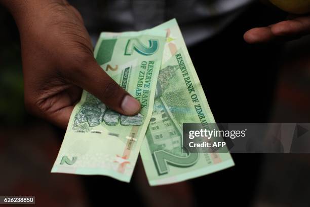 Man holds bond notes released by the Reserve Bank Of Zimbabwe in Harare central business centre on November 28, 2016. - Zimbabwe issues "bond notes"...