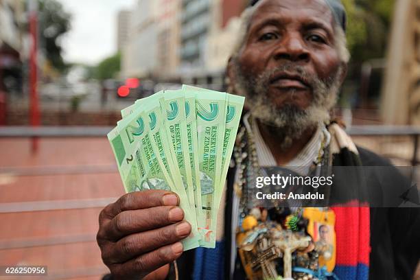 Man poses for a photograph with new banknotes as Zimbabwe Central bank launches new banknotes due to economical crisis in the country and decreasing...