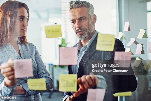 brainstorming  - team looking at adhesive notes in board room during meeting stock-fotos und bilder