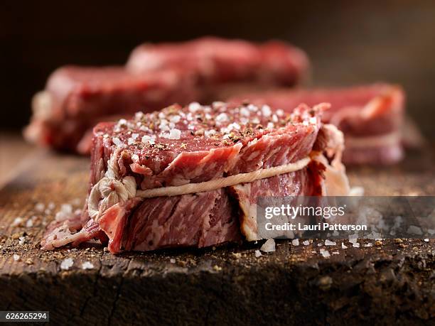 raw bacon wrapped steak fillets seasoned with salt and pepper - raw bacon stock pictures, royalty-free photos & images