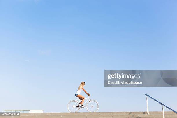 young woman cycling in the city - street clear sky stock pictures, royalty-free photos & images