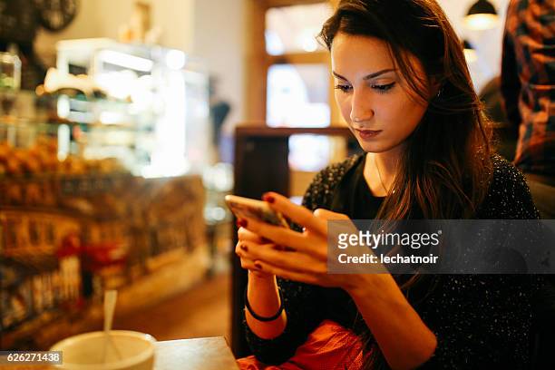 mujer joven usando teléfono inteligente en el café de berlín - universal inside 2016 in berlin fotografías e imágenes de stock