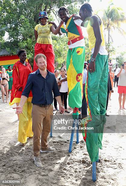 Prince Harry meets stilt walkers on Grand Anse Beach as he visits Mangrove restoration projects ahead of visiting the coral reef on the ninth day of...