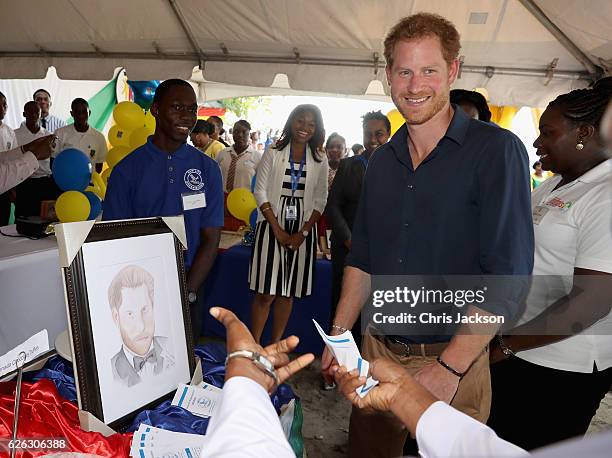 Prince Harry is presented with a portrait as he visits mangrove restoration projects on Grand Anse Beach ahead of visiting the coral reef on the...
