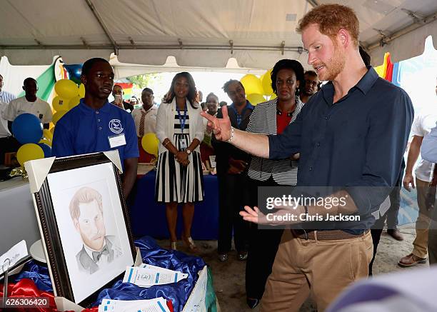 Prince Harry is presented with a portrait as he visits mangrove restoration projects on Grand Anse Beach ahead of visiting the coral reef on the...