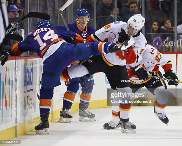 Matthew Tkachuk of the Calgary Flames checks Thomas Hickey of the New York Islanders during the first period at the Barclays Center on November 28,...