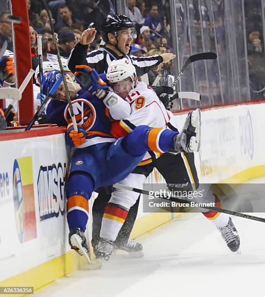 Adam Pelech of the New York Islanders is checked into the boards by Micheal Ferland of the Calgary Flames during the second period at the Barclays...