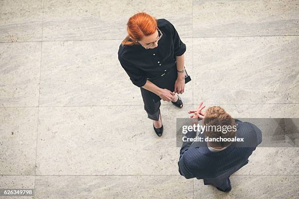 businessman and businesswoman talking in the lobby overhead shot - overhead talking stock pictures, royalty-free photos & images