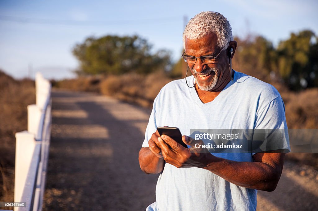Black Man using smartphone on mountain trail