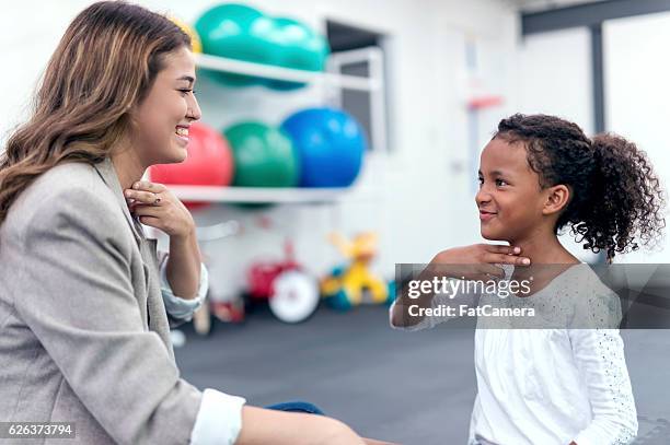 female therapist helping african american girl in speech therapy exercise - speech therapy imagens e fotografias de stock