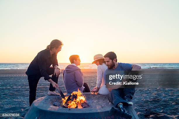 friends hanging out on the beach with a fire - fire pit stock pictures, royalty-free photos & images