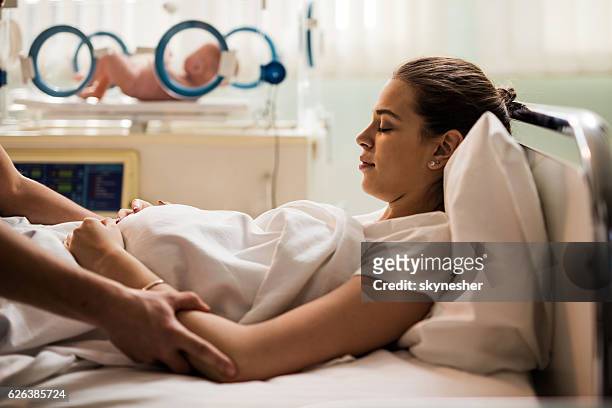 junge mutter ruht sich nach der geburt im entbindungsraum aus. - family photo in the delivery room stock-fotos und bilder