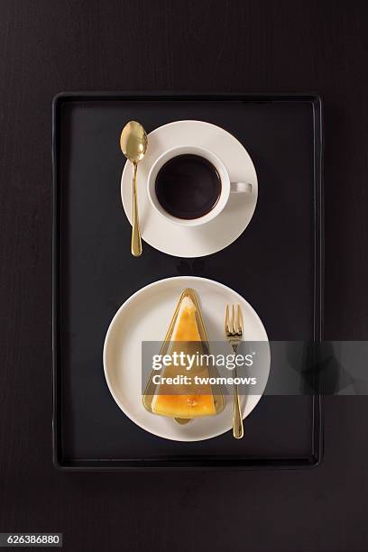 flat lay overhead view black coffee and cheese cake on black background. - coffee cake stockfoto's en -beelden