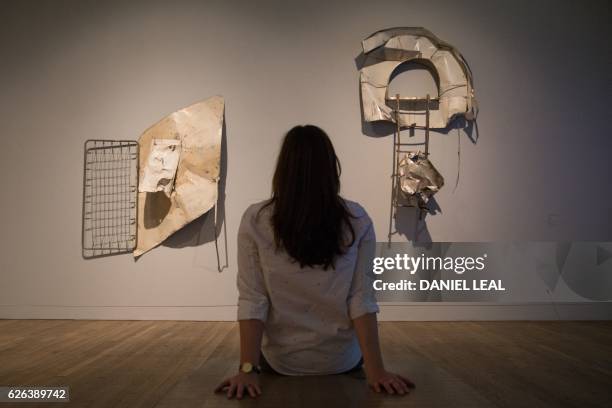 An employee poses alongside art works entitled left, 'Albino Spring glut , 1987' and right, Balcone Glut , 1987' by US artist Robert Rauschenberg...