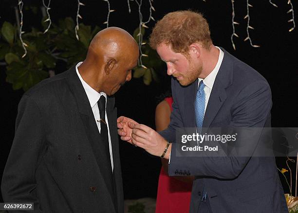 Prince Harry awards Reginald Sparks with a British Empire Medal at a reception at the Spice Island Beach Resort on November 29, 2016 in Grenada....