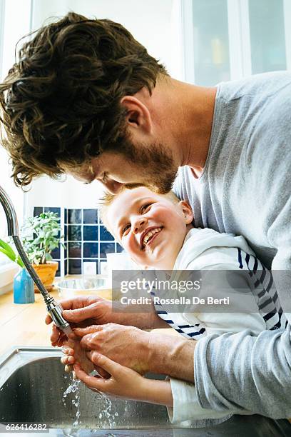 père se lavant les mains des fils dans l’évier de cuisine après avoir cuisiné ensemble - child washing hands photos et images de collection