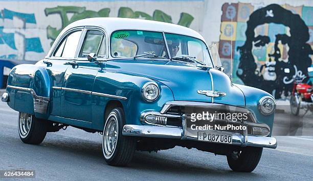 An old car passes by Che graffiti, a scene from the street, in Havana city center, on November 28 the third day after Fidel Castro, Cuba's historic...