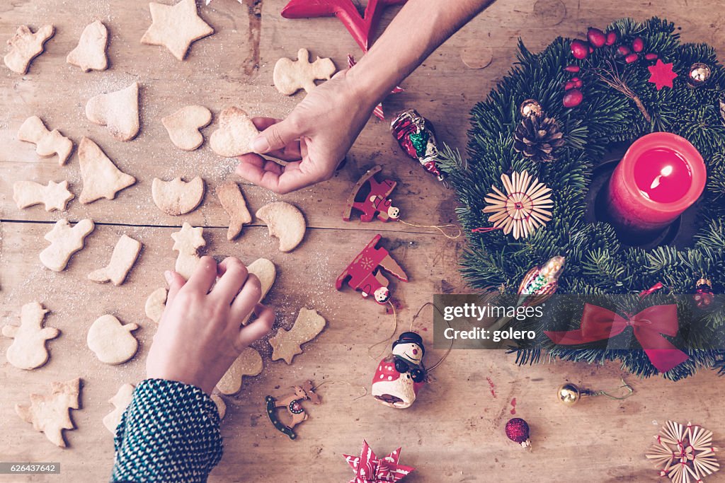 自作クッキーを持つ手で素朴な木製のクリスマステーブル