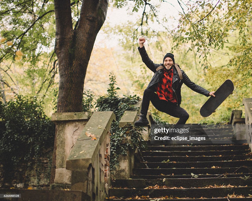 Hipster jumping with skateboard