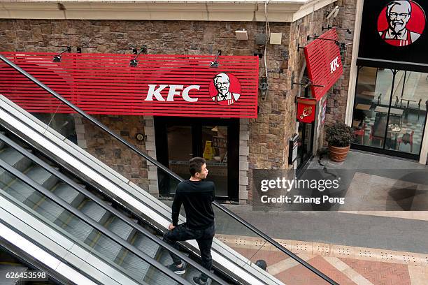 Man stands on an escalator past a KFC restaurant. As the largest restaurant chain in China, with more than 7,000 outlets, KFC makes new strategy...