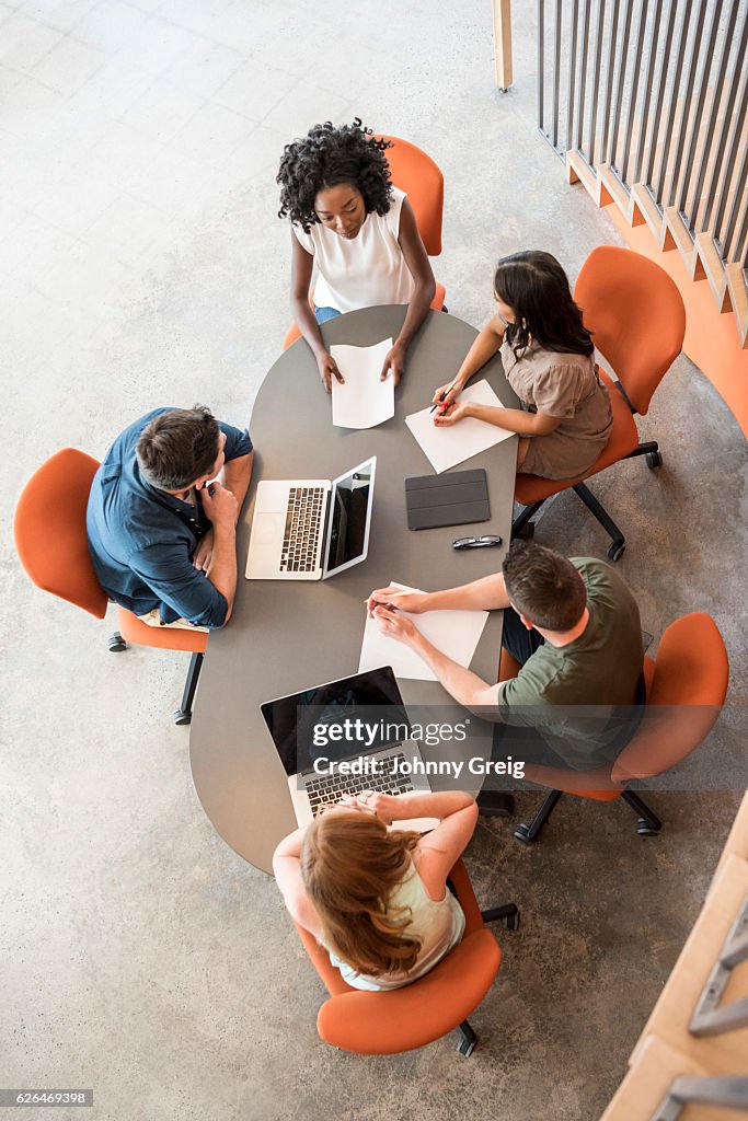 Overhead view of five business people at table in meeting