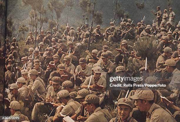 View of armed troops of the Chinese People's Liberation Army or armed forces of the People's Republic of China, sitting together on a mountainside...