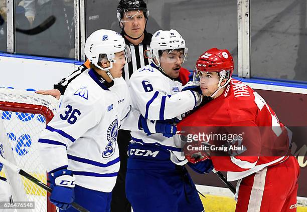 Stephen Gibson and Austin Osmanski of the Mississauga Steelheads mix it up with Liam Hawel of the Sault Ste. Marie Greyhounds during game action on...