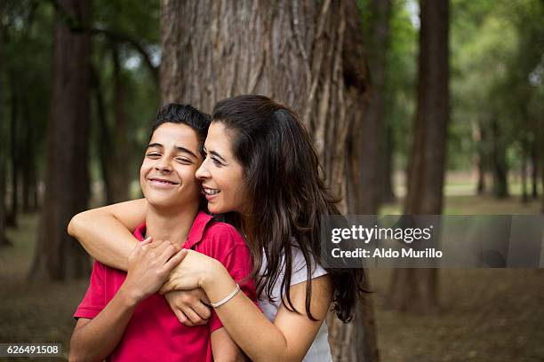 affectionate latin mother embracing teen son and smiling - mexican mothers day 個照片及圖片檔