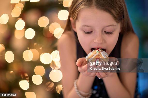 girl (9-10) eating a gingerbread house - free tiny girls stock-fotos und bilder