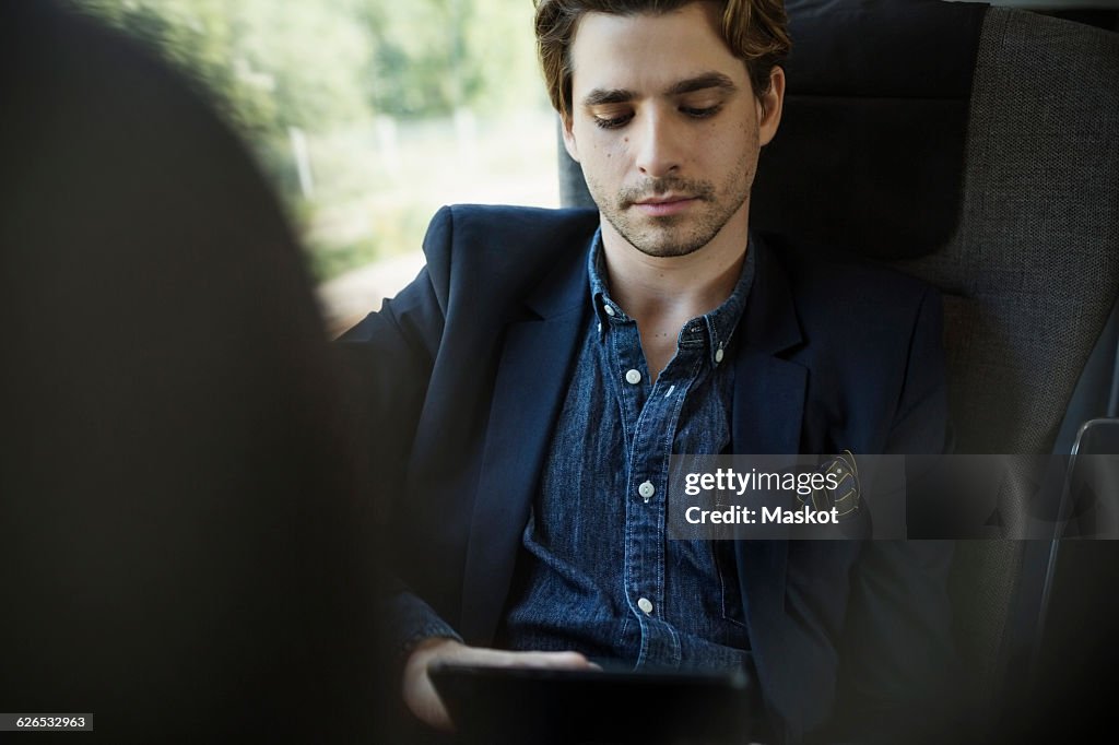 Businessman using digital tablet in train