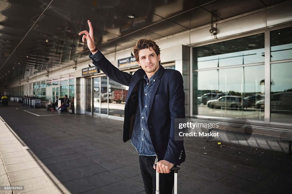 Businessman hailing taxi while standing outside airport