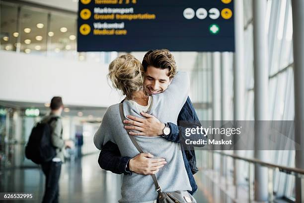 happy businessman embracing colleague at airport - femmes de dos enlacée photos et images de collection